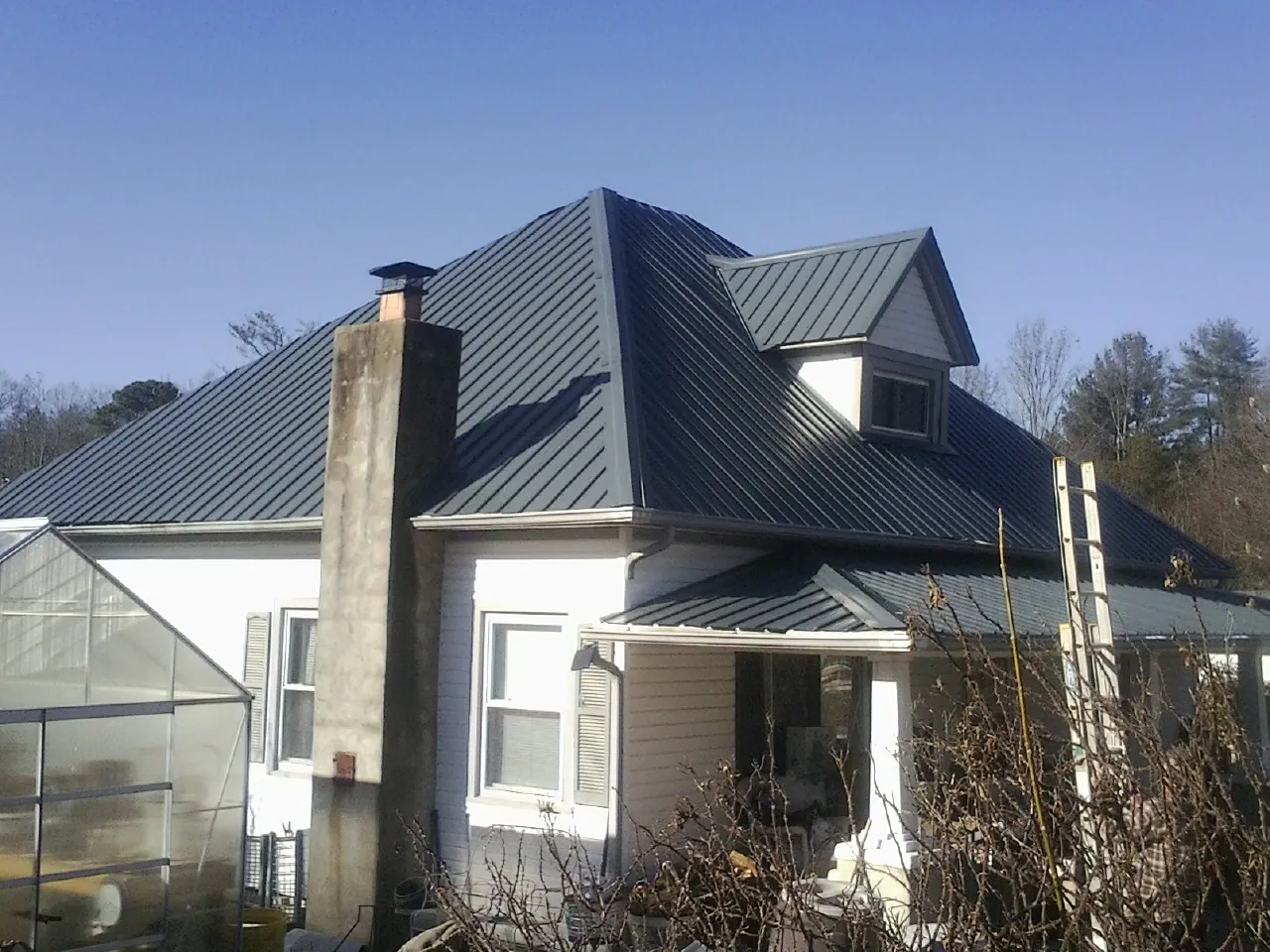 Dark blue standing seam metal roof on a white farmhouse with dormer — Slate & Tile Roof Repair by Roofing Brothers in Channahon