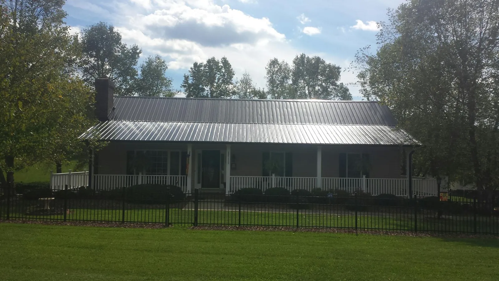 Gray metal roof on a brick ranch with a full width front porch — Gutter Guard Installation work by our crew in Channahon