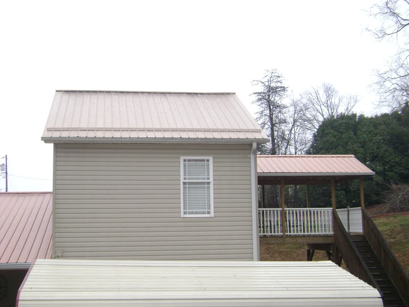 Tan metal roofs on a two story addition and attached porch, from a Roof Replacement job in Channahon