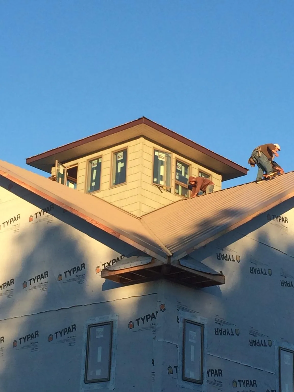 Roofers working around a rooftop cupola on a new metal roof at sunset — Roof Waterproofing in Channahon by Roofing Brothers